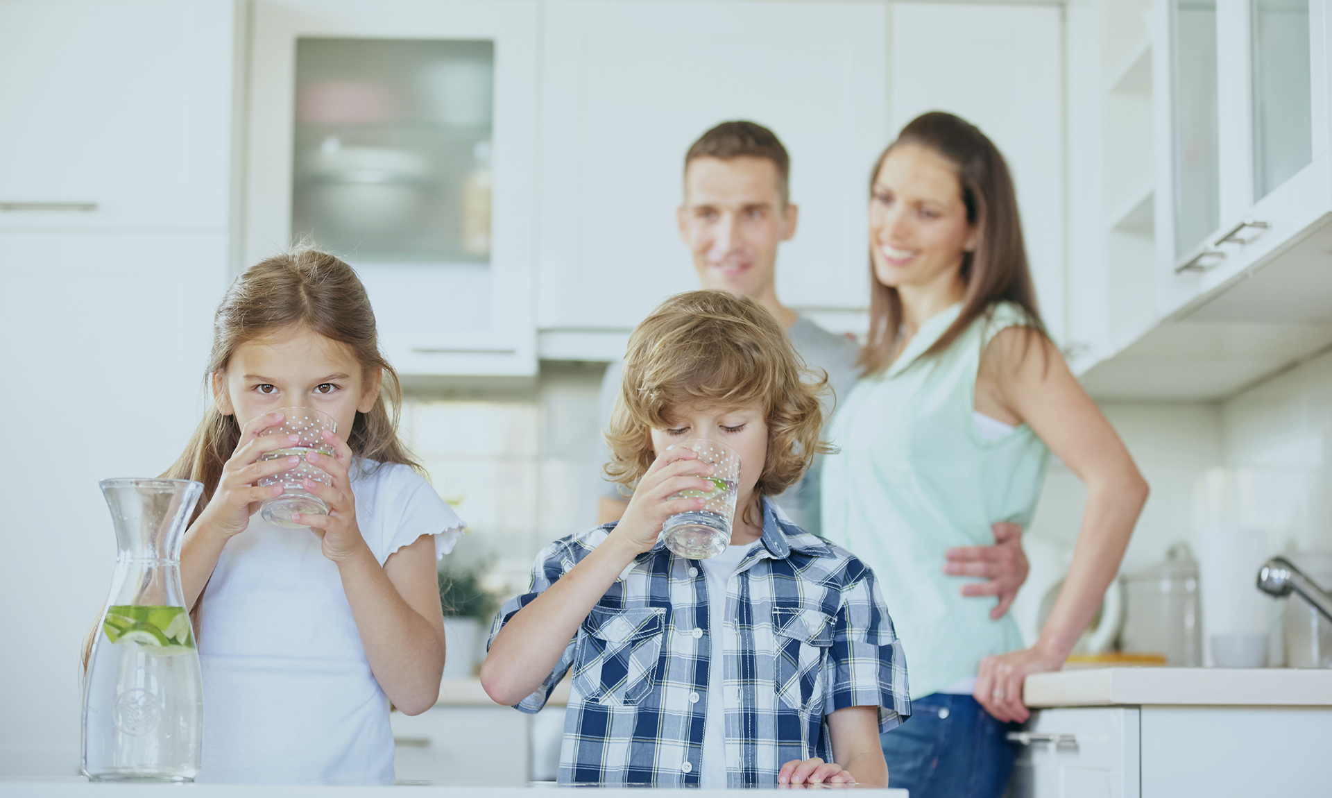 Boy and girl drinking water with lime in the kitchen while the p